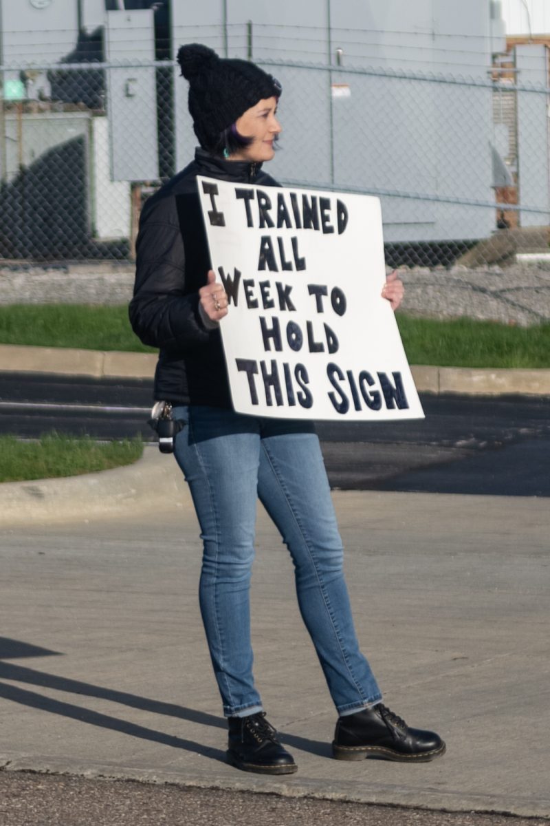 Kim Shuman holds up a funny sign to cheer on runners at the Black Squirrel 5k and 1-Mile Walk/Roll/Run on April 13, 2024.