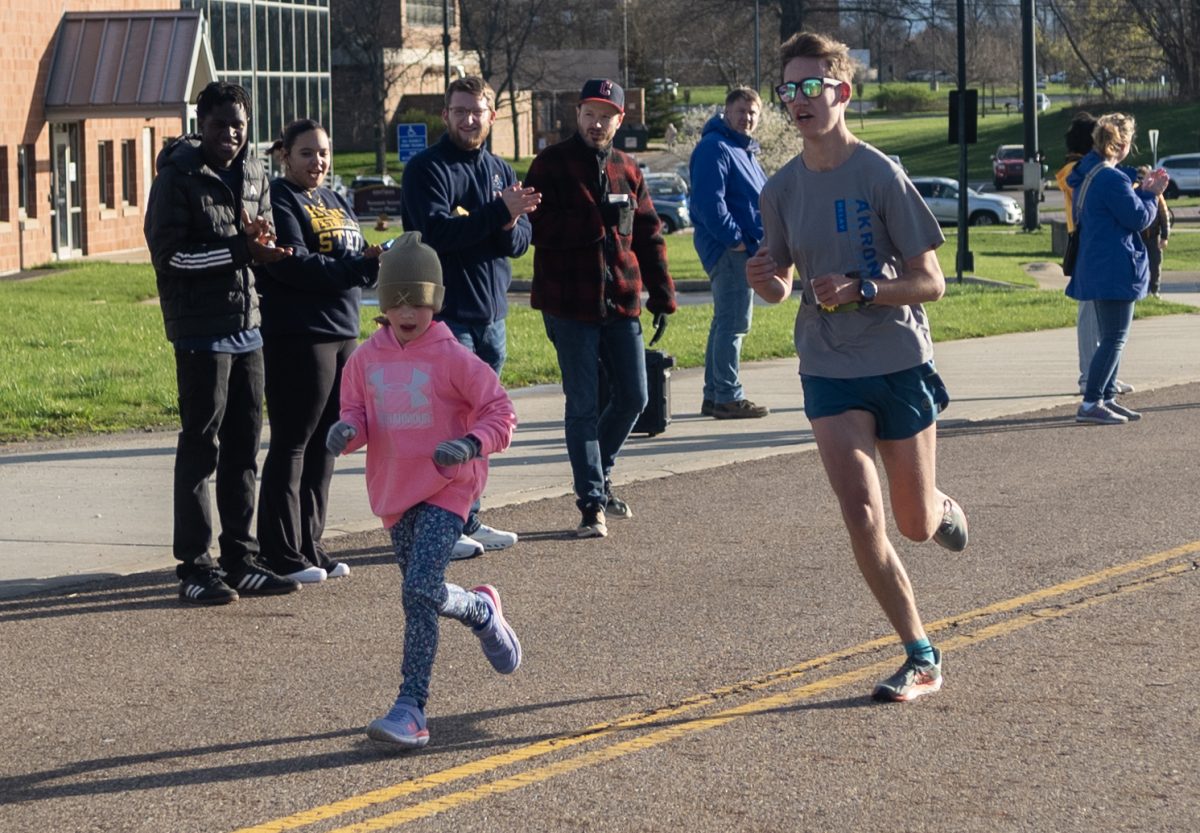 A merger of participants, Adin Merritt passes a young child, who participated in the 1-mile, on his way to an 8th place finish at the Black Squirrel 5k on April 13, 2024.