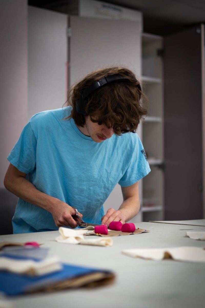 Sawyer Lulei, junior fashion design major, cuts fabric in the junior studio in Rockwell on April 18, 2024.