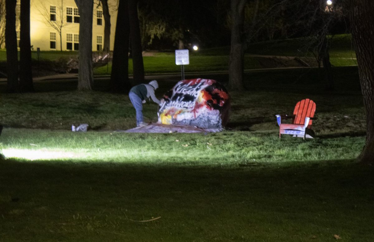 A sisguised figure spray paints the message Kyle did nothing wrong on Kent States campus rock April 15, 2024.