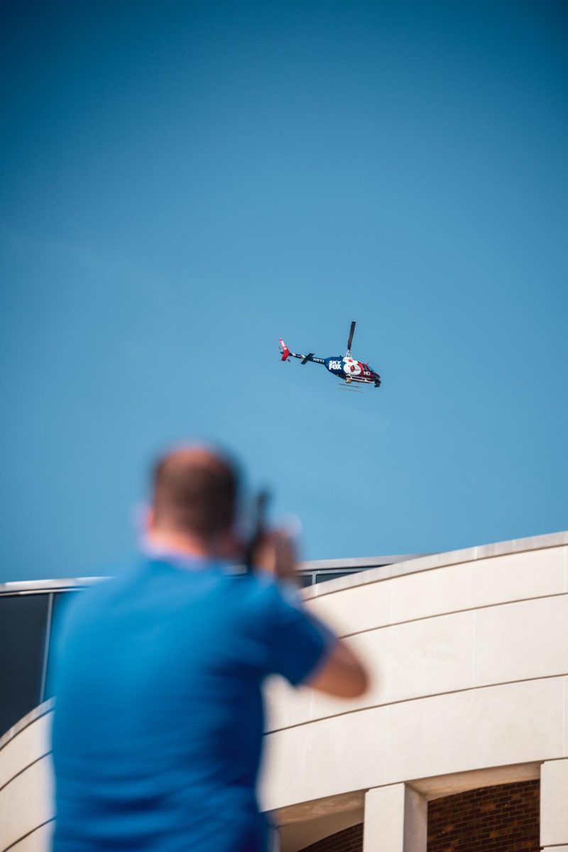 A person films the Fox News helicopter as it flies overhead April 16, 2024