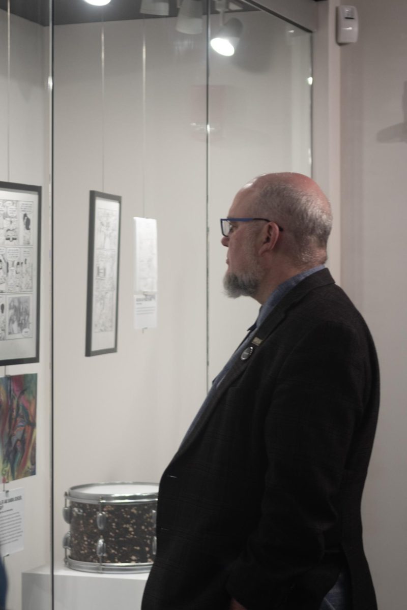 Kenneth Burhanna, the Dean of University Libraries, peruses the Graphic Content display in the Reflections Gallery at the May 4th Visitors Center.