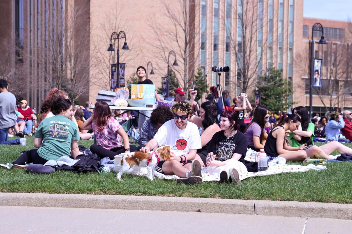 Kent State students sit on the grass by the Risman Plaza to wait for the solar eclipse on April 8, 2024. 