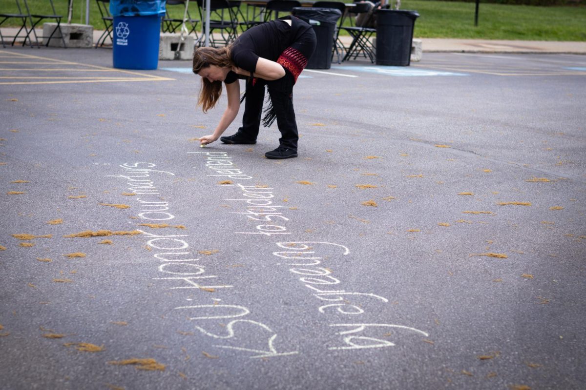 Sara Koopman, peace studies professor at Kent State University, writes with chalk in the Taylor Hall parking lot on May 4, 2024.