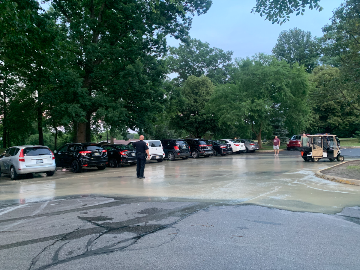 A Kent State University police officer stands in the flooded parking lot of Leebrick Hall on Monday, June 17, after a water pipe submerged the area.