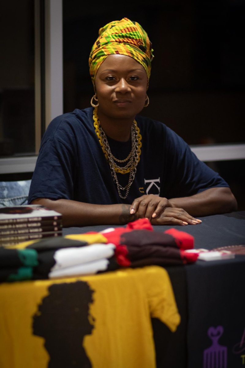 Dr. Tameka Ellington, Speaker, Author, Entrepreneur, and past Kent State professor, sits at her table where she has books that she has written and tee shirts for sale at the Black Alumni Chapter Homecoming Marketplace and Dance on Sept. 27, 2024.