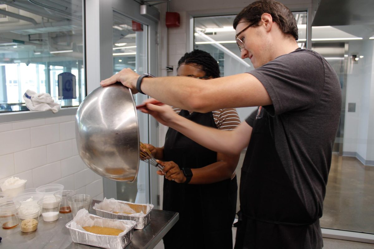 Senior, Brianna Peake and Senior Cameron Fox pour the pumpkin dough for their recipe, pumpkin crumb cake, during a culinary class in the DI Hub on September 13, 2024. 