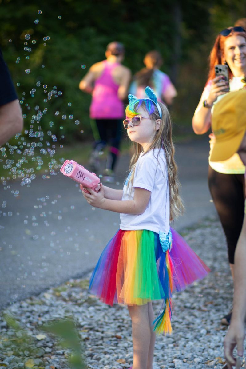 Autumn Orwick blows bubbles at runners as they pass by at the Drag 5k on Oct. 11, 2024.