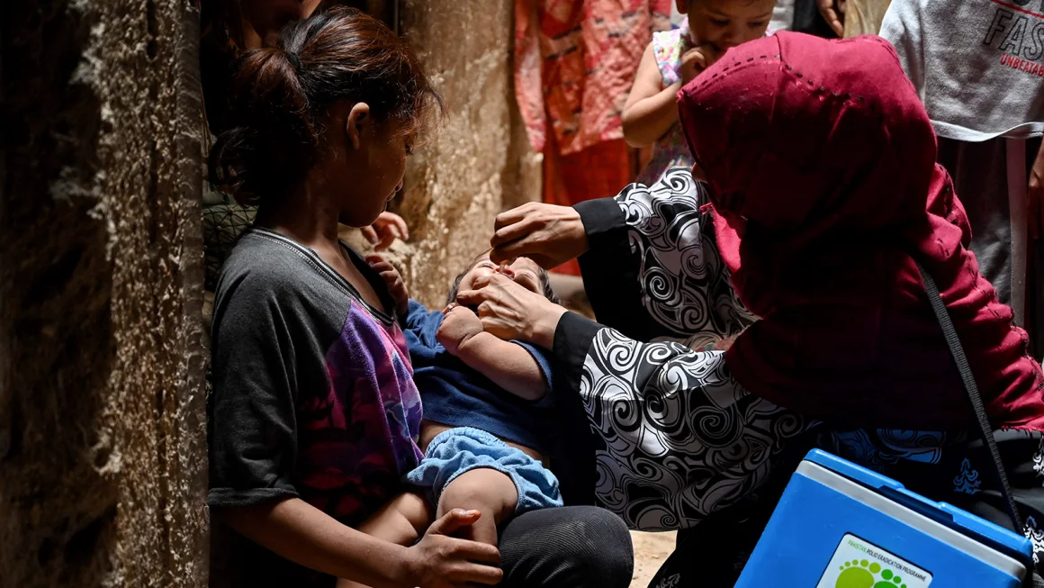 A health worker administers polio vaccine drops to a child during a vaccination campaign in Karachi on June 3, 2024. 