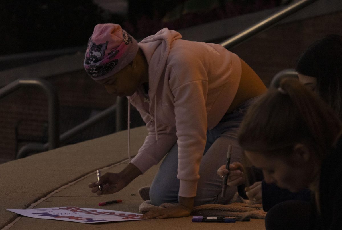 A student decorates a sign before the Take Back the Night march, Oct. 8, 2024.