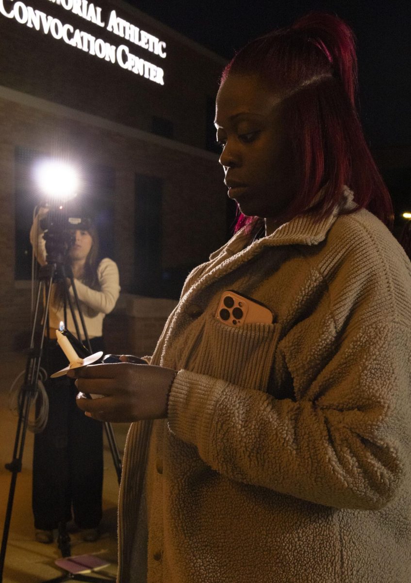 Oct. 8, 2024, a student lights a candle for a moment of silence at the Take Back the Night march.