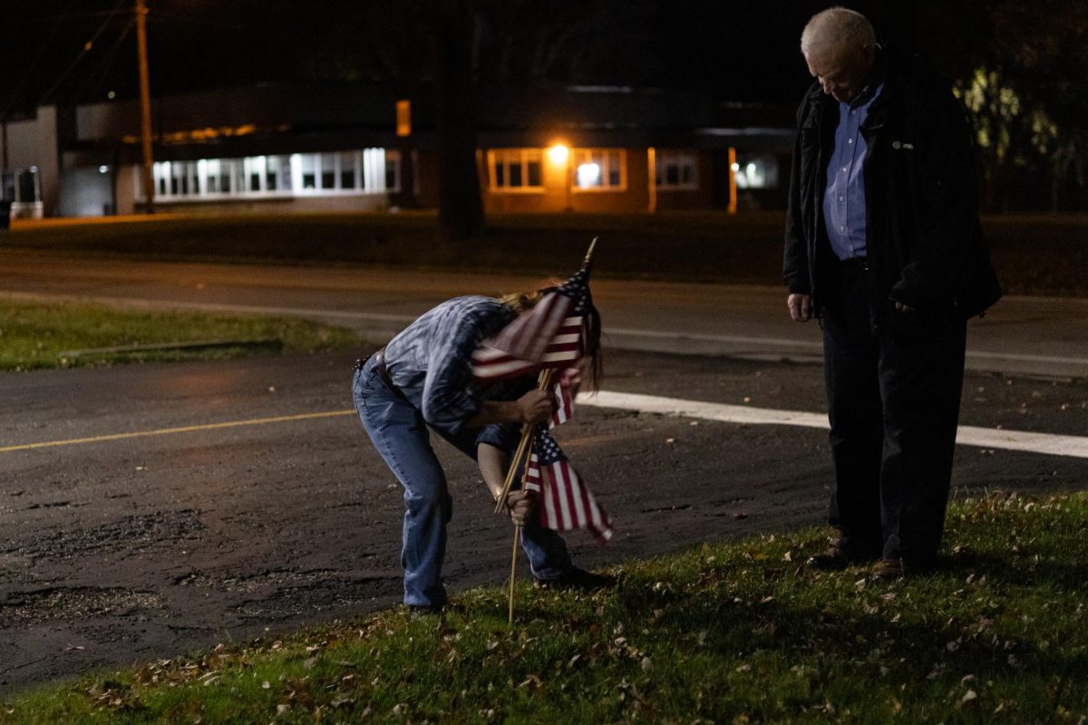 Jean Reid, a poll worker, is placing flags to mark the driveway to Ravenna Elk Lodge, a voting location on Nov. 5th, 2024.